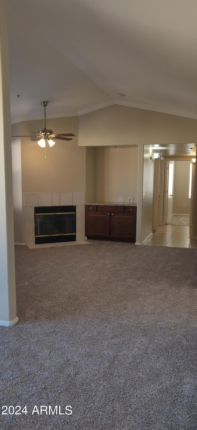 unfurnished living room with lofted ceiling, ceiling fan, a tile fireplace, and carpet flooring