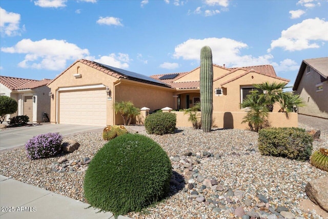 mediterranean / spanish-style house featuring an attached garage, driveway, roof mounted solar panels, and stucco siding