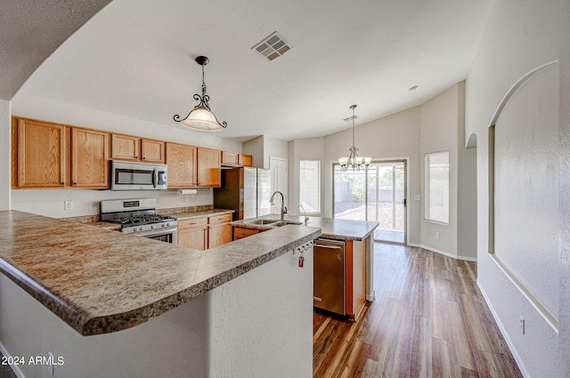 kitchen featuring dark wood-type flooring, sink, decorative light fixtures, stainless steel appliances, and a kitchen island with sink