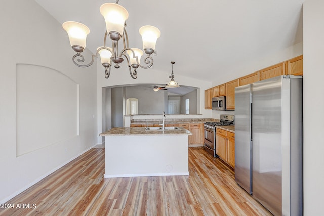 kitchen featuring sink, appliances with stainless steel finishes, hanging light fixtures, a center island with sink, and light wood-type flooring