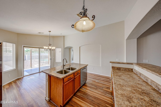 kitchen with sink, hanging light fixtures, light wood-type flooring, dishwasher, and a kitchen island with sink