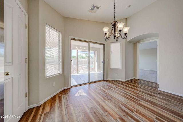 unfurnished dining area with a notable chandelier and light wood-type flooring