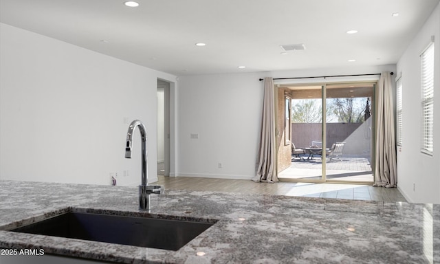 kitchen featuring sink, light hardwood / wood-style flooring, and stone counters