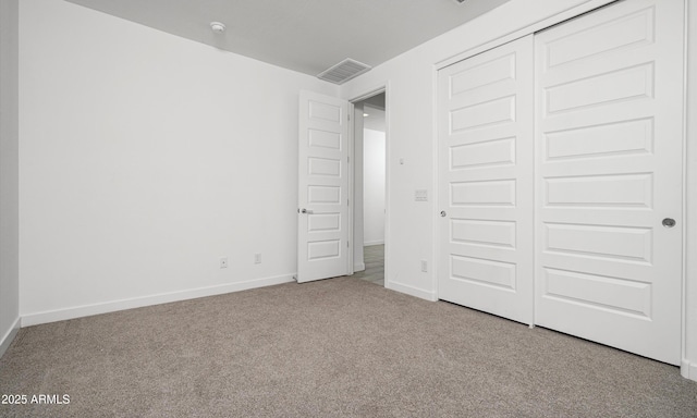 unfurnished bedroom with light colored carpet and a closet