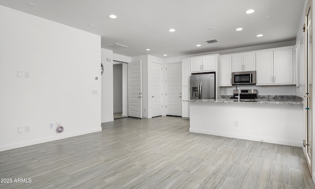 kitchen with stone countertops, white cabinets, and appliances with stainless steel finishes