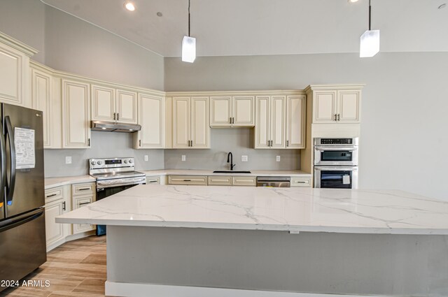 kitchen featuring appliances with stainless steel finishes, pendant lighting, sink, and light wood-type flooring