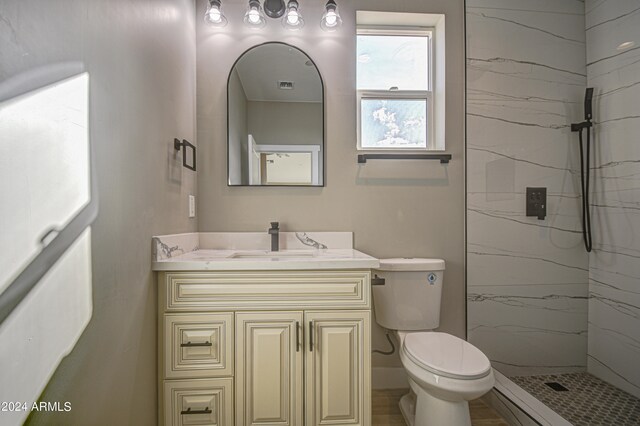 bathroom featuring toilet, a tile shower, and vanity