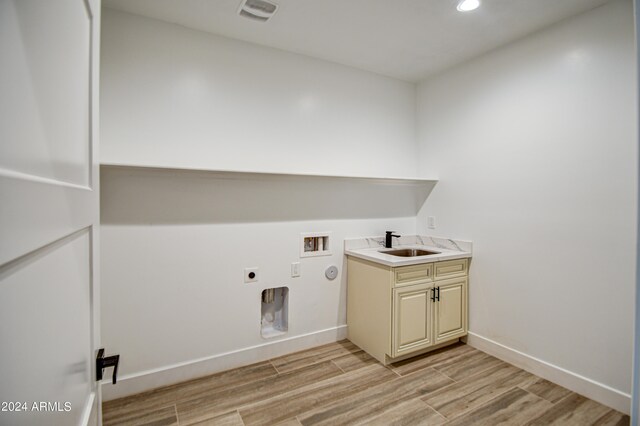 clothes washing area with light hardwood / wood-style flooring, sink, cabinets, and hookup for an electric dryer