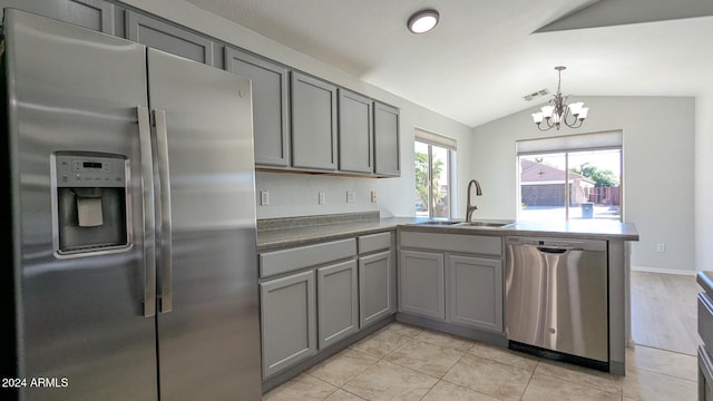 kitchen with appliances with stainless steel finishes, lofted ceiling, sink, kitchen peninsula, and light tile patterned flooring