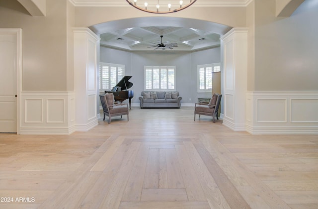 living area with light hardwood / wood-style floors, crown molding, and coffered ceiling