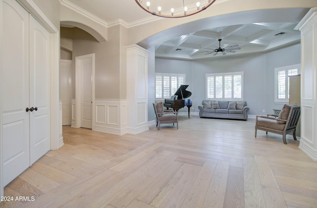 sitting room featuring ornamental molding, beam ceiling, light hardwood / wood-style flooring, coffered ceiling, and ceiling fan with notable chandelier