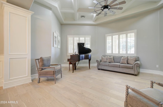 living room featuring coffered ceiling, ornamental molding, beamed ceiling, ceiling fan, and light wood-type flooring