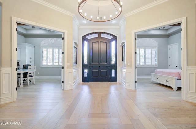 foyer with light wood-type flooring, a healthy amount of sunlight, and crown molding