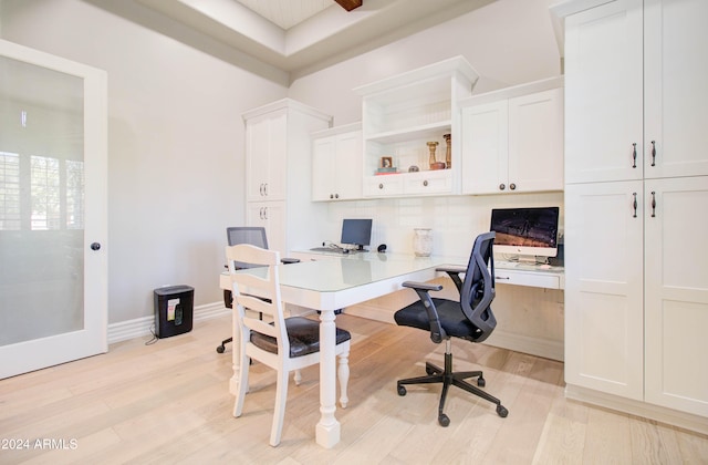 home office featuring light wood-type flooring and built in desk