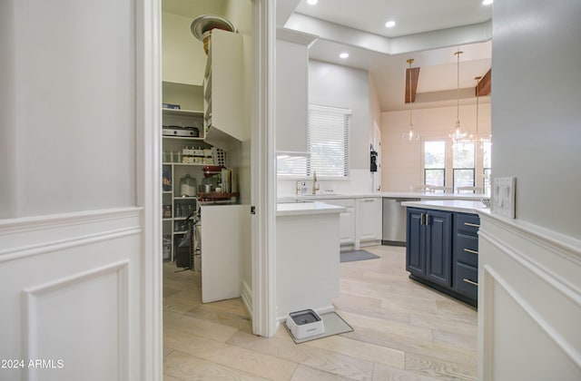 kitchen featuring white cabinetry, sink, stainless steel dishwasher, light hardwood / wood-style floors, and blue cabinets