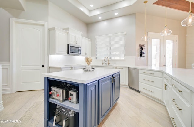 kitchen featuring white cabinetry, appliances with stainless steel finishes, blue cabinetry, and light hardwood / wood-style flooring