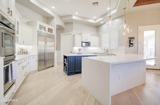 kitchen featuring white cabinetry, blue cabinetry, appliances with stainless steel finishes, kitchen peninsula, and light hardwood / wood-style flooring