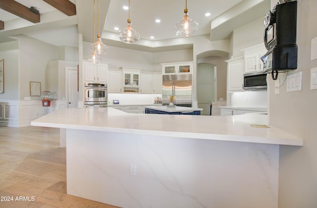 kitchen with light wood-type flooring, white cabinetry, appliances with stainless steel finishes, hanging light fixtures, and kitchen peninsula