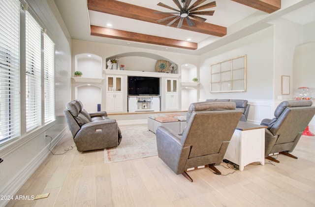 living room featuring ceiling fan, light hardwood / wood-style floors, and beamed ceiling