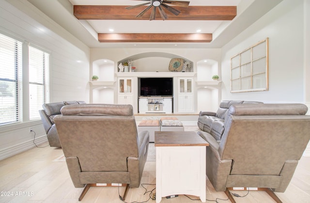 living room featuring beamed ceiling, a wealth of natural light, ceiling fan, and light hardwood / wood-style flooring