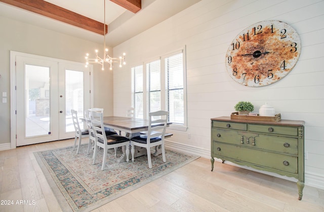 dining space featuring french doors, wooden walls, an inviting chandelier, light hardwood / wood-style floors, and beamed ceiling