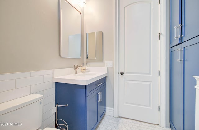 bathroom featuring toilet, vanity, and tile walls