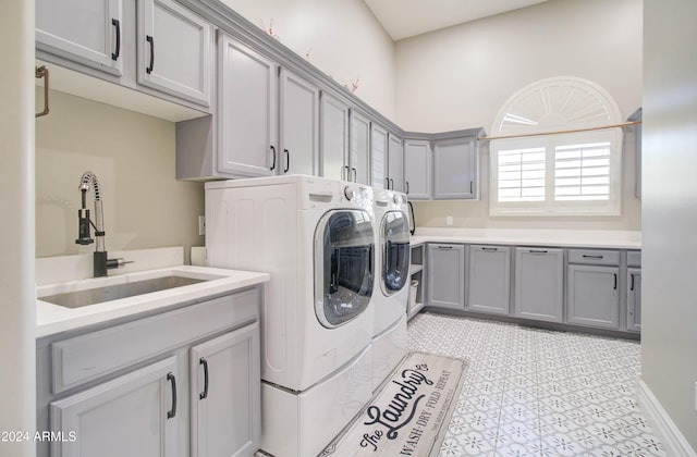 laundry room featuring washing machine and dryer, cabinets, and sink