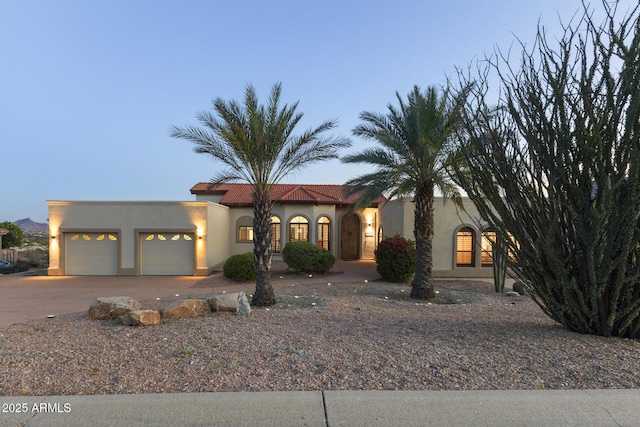 view of front of home with driveway, a tiled roof, an attached garage, and stucco siding