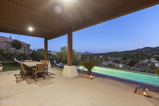 view of patio with outdoor dining area, fence, a mountain view, and a fenced in pool