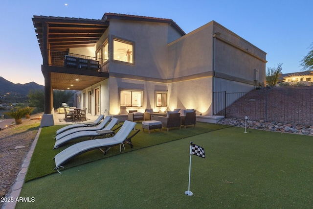 back of property at dusk featuring an outdoor living space, a patio area, a balcony, and stucco siding