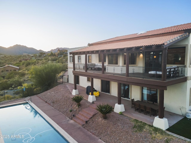 back of property with a fenced in pool, a patio, fence, a mountain view, and stucco siding