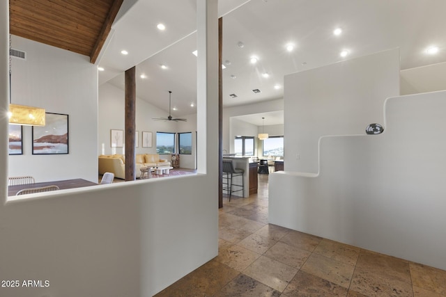 corridor with high vaulted ceiling, recessed lighting, visible vents, and stone tile floors