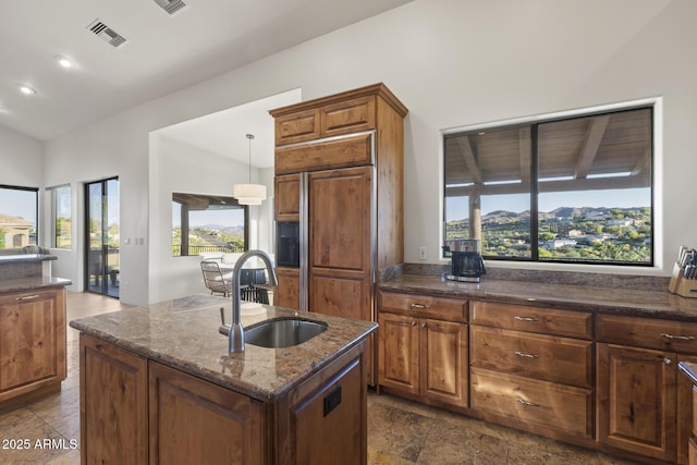 kitchen featuring lofted ceiling, visible vents, paneled built in fridge, a sink, and dark stone counters