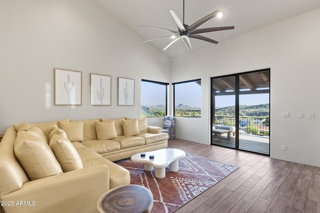 living room with ceiling fan, high vaulted ceiling, and wood finished floors