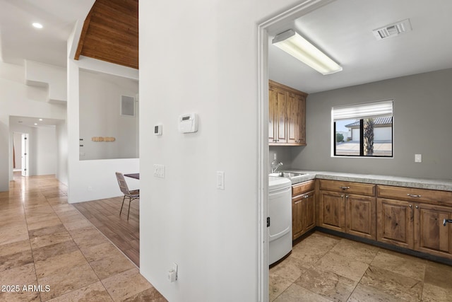 kitchen featuring a sink, visible vents, light countertops, brown cabinets, and washer / dryer