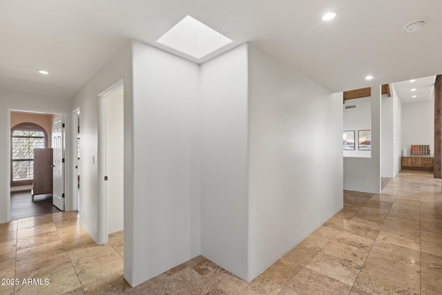 hall featuring a skylight, stone finish flooring, and recessed lighting