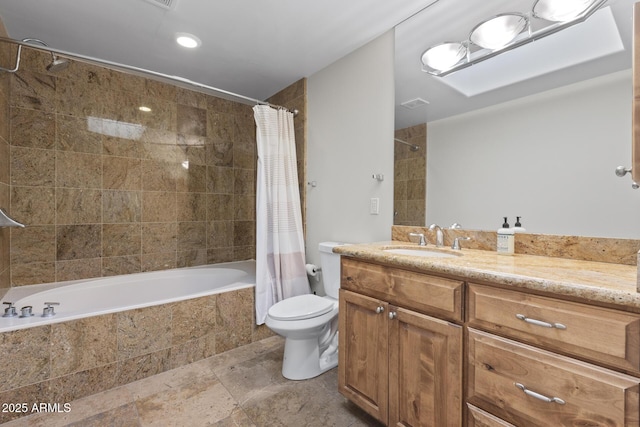 bathroom featuring tiled shower / bath, stone finish floor, vanity, and toilet