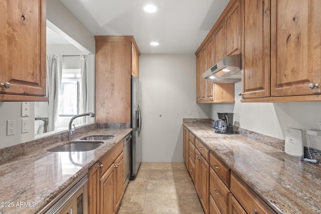 kitchen featuring under cabinet range hood, stainless steel appliances, a sink, and brown cabinetry