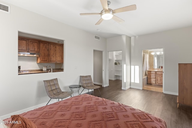 bedroom with a spacious closet, dark wood-style flooring, visible vents, and baseboards