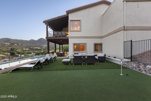 back of house featuring a mountain view, a balcony, an outdoor hangout area, a fenced in pool, and stucco siding