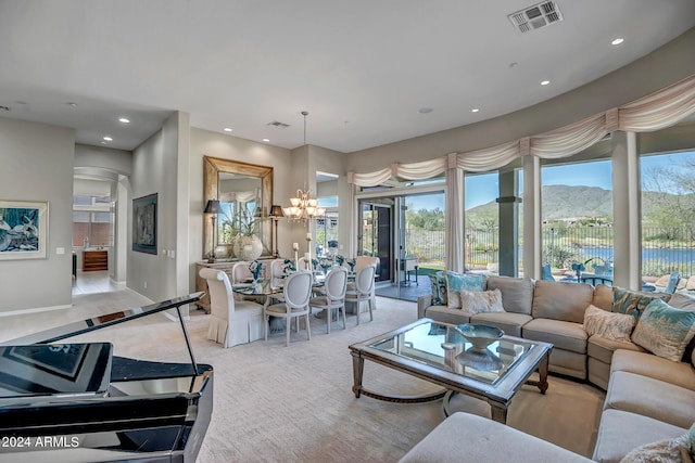 living room with light colored carpet, a chandelier, and a water and mountain view