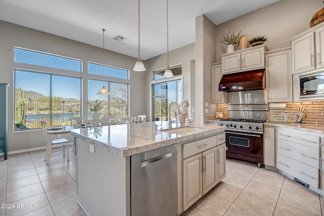 kitchen with sink, tasteful backsplash, decorative light fixtures, appliances with stainless steel finishes, and an island with sink