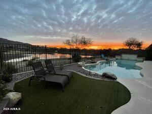 pool at dusk featuring a patio area and a water view