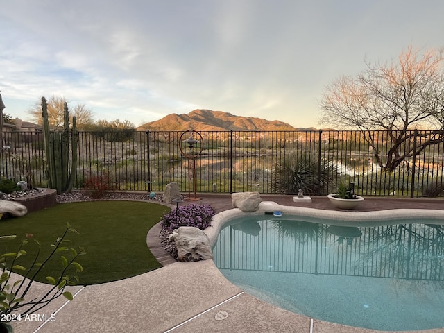 pool at dusk with a yard and a mountain view