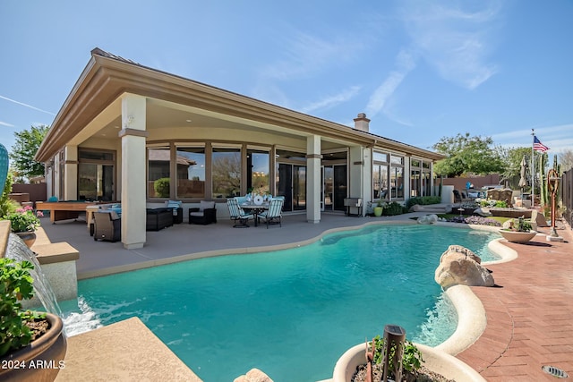 view of swimming pool with an outdoor living space, pool water feature, and a patio area