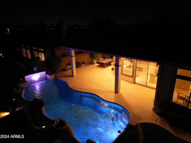 pool at night featuring a patio