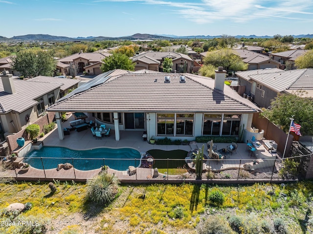 rear view of property with a fenced in pool, a mountain view, a patio, and solar panels