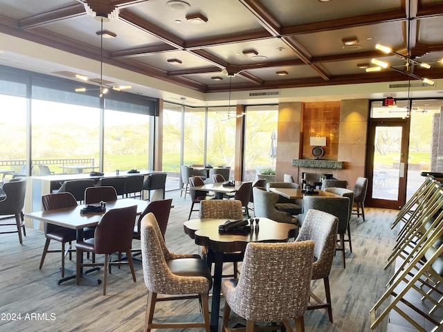 dining area featuring an inviting chandelier, coffered ceiling, a tiled fireplace, and light hardwood / wood-style floors