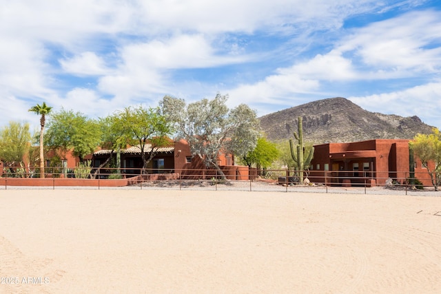 surrounding community with a mountain view, fence, and volleyball court