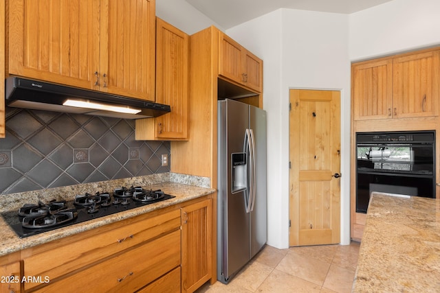 kitchen featuring light stone countertops, backsplash, light tile patterned floors, under cabinet range hood, and black appliances
